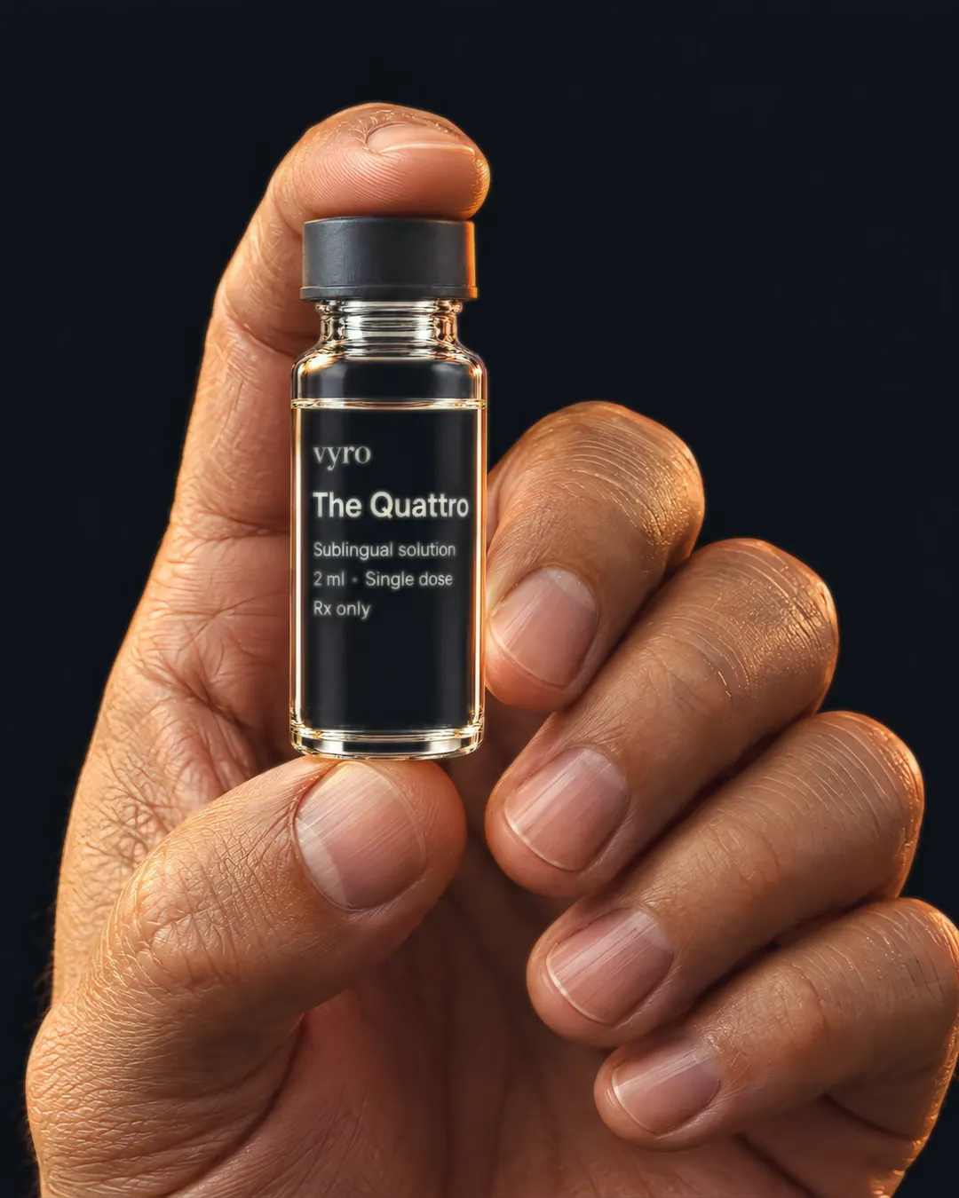 Close-up of a man's hand holding the small clear glass vial of The Quattro between thumb and forefinger, its graphite cap and the off-white print on the glass in focus: The Quattro, Sublingual solution, 2 ml, single dose.